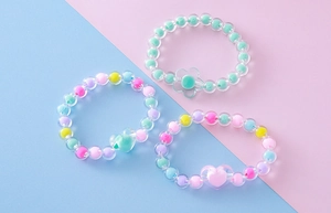 Vista de detalle de pulseras de cuentas acrílicas coloridas con dijes infantiles
