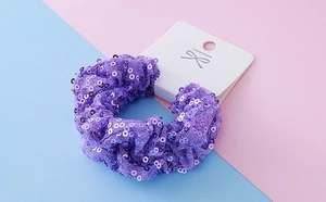 Detail of purple sequin mesh hair scrunchie on a display card with festive design