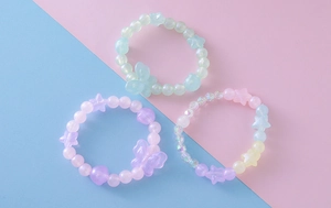 Détail de trois bracelets de perles colorés avec breloques étoiles et papillons
