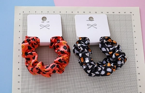 Detail of Halloween hair scrunchies with pumpkin and wizard hat prints on satin fabric