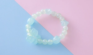 Vue détaillée du bracelet de perles vert menthe avec lustré nacré et papillon