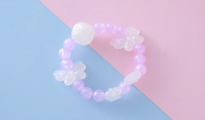 Détail du bracelet en perles roses et violettes avec papillon blanc et perles rondes
