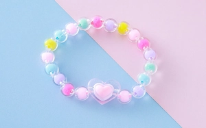 Detalle de cuentas acrílicas coloridas con colgante de corazón para pulsera infantil