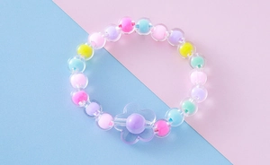 Primer plano de pulsera elástica con cuentas de colores, flor de acrílico y núcleos vibrantes
