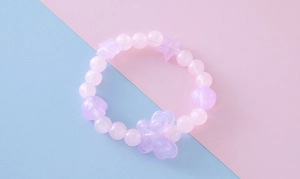 Vue détaillée du bracelet de perles roses et mauves avec breloques étoile et papillon