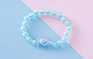 Detalle de la pulsera de cuentas de caramelo de acrílico con colgante de corazón azul
