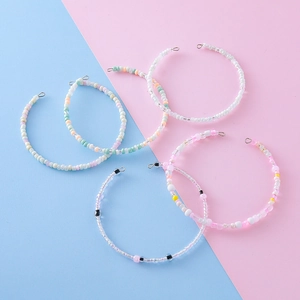 Set of five colorful handmade seed bead bracelets with metal clasps on a pastel background