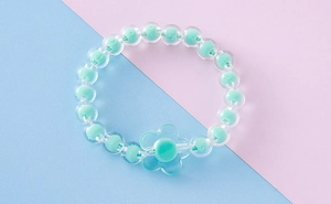 Primer plano de pulsera infantil de cuentas pastel con dije de flor de acrílico
