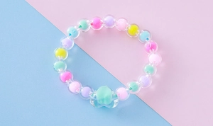 Primer plano de cuentas acrílicas de colores macaron y pulsera con dije de corazón