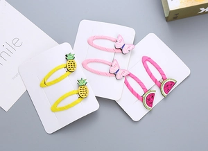 Dettaglio di fermagli per capelli con glitter, motivi ananas e fiocchi in tessuto intrecciato