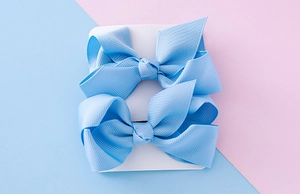 Détail de barrettes à nœuds bleu clair en ruban côtelé sur une carte de support