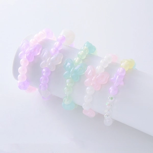 Gros plan de bracelets en perles macaron pastel avec breloques papillon et étoile pour filles
