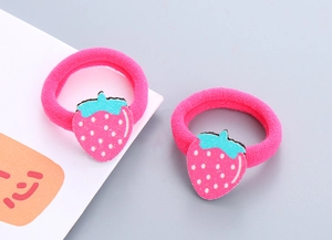 Détail de deux chouchous élastiques roses avec de jolis charmes de fraises pour enfants