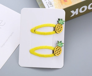Dettaglio di fermagli per capelli a forma di ananas giallo con foglie glitterate