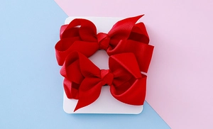Détail de nœuds en ruban gros-grain rouge sur carte avec fond rose et bleu clair