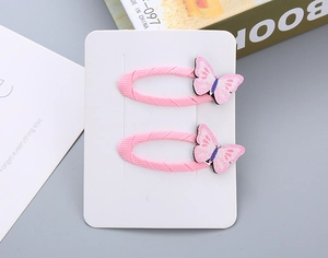 Dettaglio di fermagli BB in tessuto rosa con decorazione farfalla glitterata per bimbi