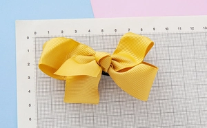 Vue détaillée d'un nœud papillon en ruban jaune montrant la taille de 12 cm sur règle
