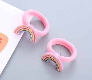 Gros plan d'élastiques à cheveux roses pour enfants avec breloques arc-en-ciel pailletées