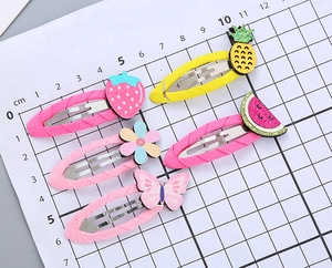 Dettaglio di 5 mollette per capelli con cartoni animati, frutta e farfalle colorate