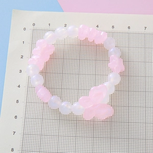 Bracelet enfant perles roses et blanches avec breloques papillon sur planche graduée