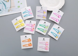 Détail d'un lot de barrettes BB colorées avec breloques de dessins animés fruits et desserts