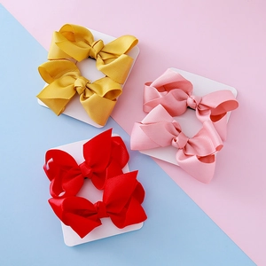 Trois paires de nœuds papillon en ruban gros-grain rouge, rose et jaune sur carte