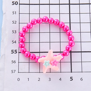 Detailed macro view of girls' hot pink pearl bead bracelet with a resin starfish and floral charm