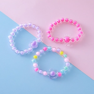 Juego de tres pulseras de cuentas acrílicas con dijes de corazón, caramelo y flor
