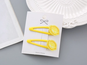 Détail de barrettes à fleurs jaune vif sur carte, montrant la finition brillante et le clip BB