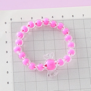Pulsera de cuentas rosas para niñas con un colgante de caramelo en fondo de cuadrícula