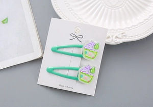 Détail de pinces BB vert menthe avec breloques gâteaux 3D sur carte de support