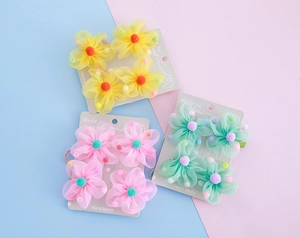 Detailansicht handgefertigter Blumen-Haarspangen aus Netzstoff in Gelb, Rosa und Minze