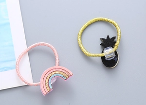 Détail de chouchous arc-en-ciel rose et ananas noir avec des élastiques pailletés