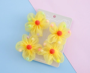 Detailansicht von vier gelben Netzblumen-Haaraccessoires mit orangen Pompons für Kinder