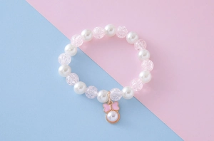 Detail of beaded child bracelet with white faux pearls and pink cracked glass beads