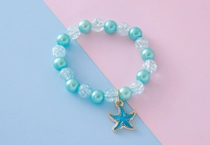 Close-up of sky blue pearls and cracked glass beads with seahorse pendant on pastel background