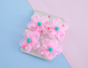 Detailansicht der rosa Netz-Haarspangen mit grünen Pompons im vierteiligen Set für Kinder