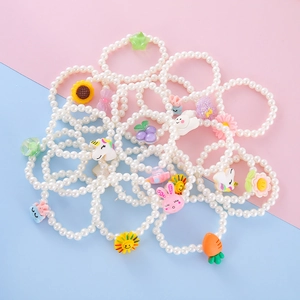 Flat lay of colorful resin cartoon charms and white pearl bracelets for kids