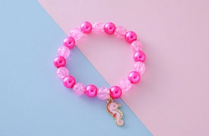 Close-up of pink imitation pearls and crackle beads bracelet with seahorse pendant