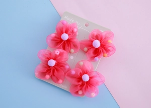 Details von vier rosa Netzblumen-Haarclips mit lila Bommeln auf einer Displaykarte