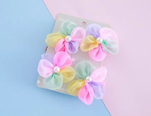 Detail von vier bunten Netzblumen-Haarclips mit Kunstperlen auf Displaykarte