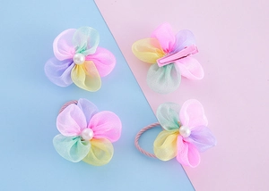 Nahaufnahme von Haarspangen und Gummis mit Netzblumen, Perlen und rosa Metallclips