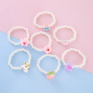 Detail of 7 children pearl bracelets with cartoon charms like rabbit, flower and peach