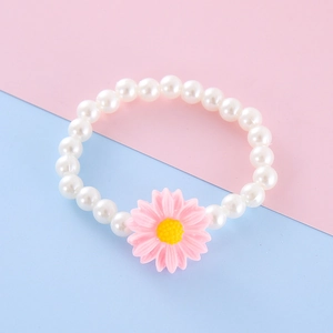 Close-up of kids resin bracelet featuring white imitation pearls and a pink daisy charm