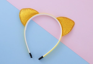 Détail d'un serre-tête oreilles de chat jaune avec paillettes dorées et dents antidérapantes