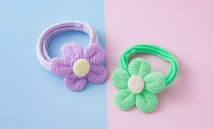 Vue détaillée des élastiques à fleurs en velours côtelé violet et vert sur fond coloré