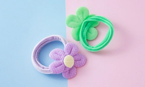 Gros plan sur des chouchous fleurs en peluche violet et vert avec texture en velours