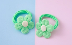 Détail d'élastiques à cheveux fleurs tricotées vert clair avec centre blanc sur fond pastel