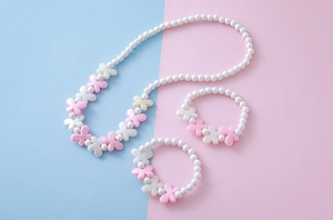 Nahaufnahme von Mädchen-Schmuckset mit rosa-weißer Perlenkette und Schmetterlingsarmbändern