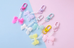Detail of candy-colored acrylic bow pendants with beaded charms on pastel backgrounds